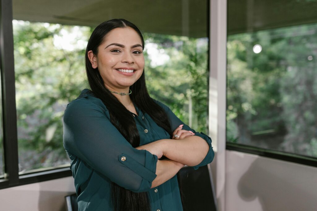 pexels-photo-7648239-7648239 Portrait of a confident businesswoman standing with arms crossed in modern office space.